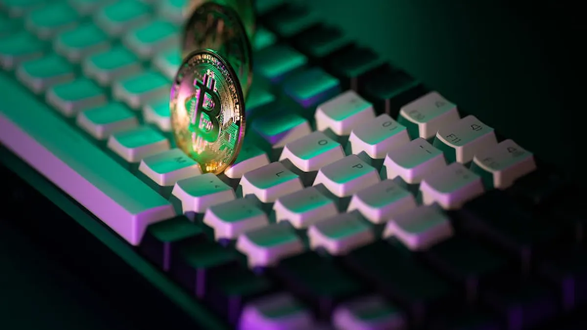 Golden Bitcoin coins on a keyboard with colorful neon lighting. Modern cryptocurrency concept.