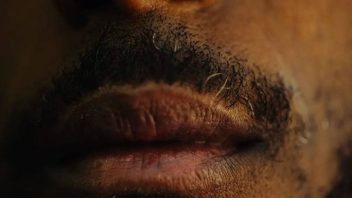Detailed close-up of a man's lips and mustache with a focus on texture.
