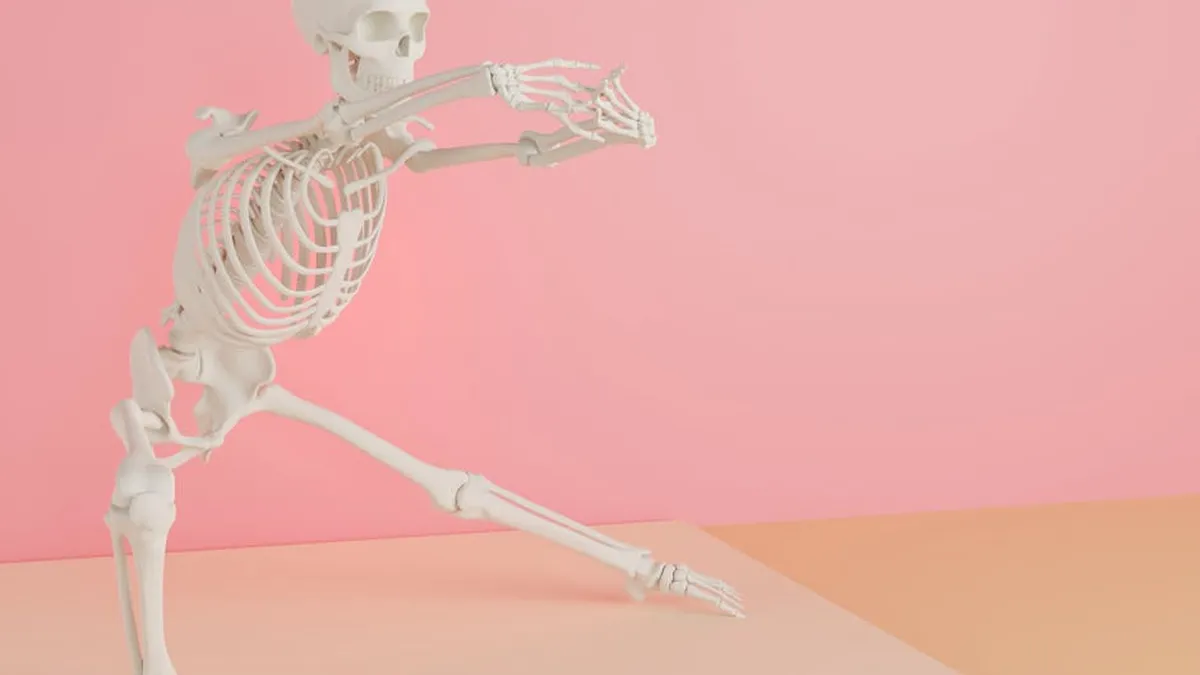 A white skeleton model striking a dynamic pose on a pink and peach background.