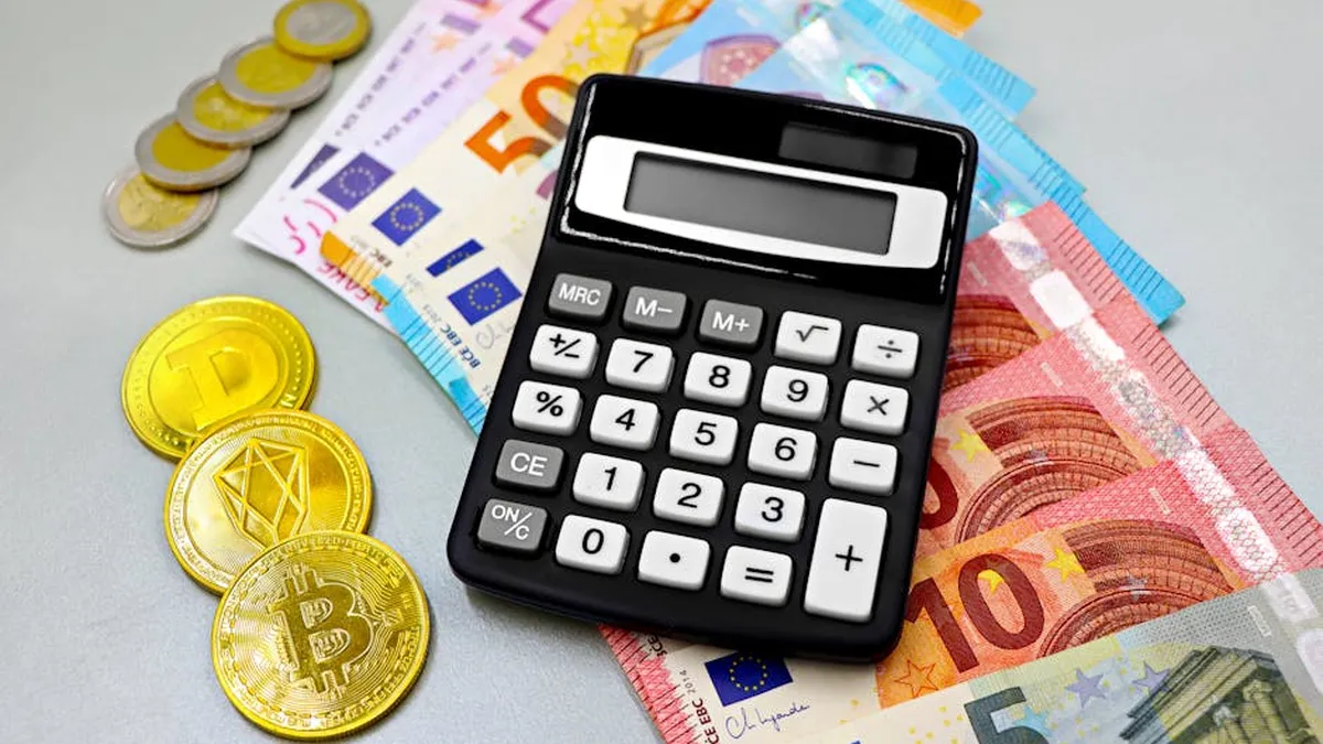 Calculator with euro banknotes and cryptocurrency coins like Bitcoin on a table.