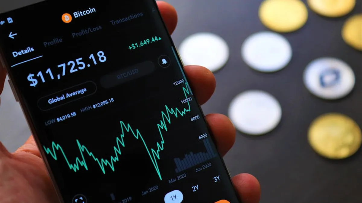 Close-up of Bitcoin trading app on smartphone showing market trends and digital coins.