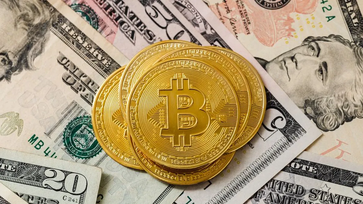 Close-up of gold bitcoin coins on US paper money, representing cryptocurrency investment.