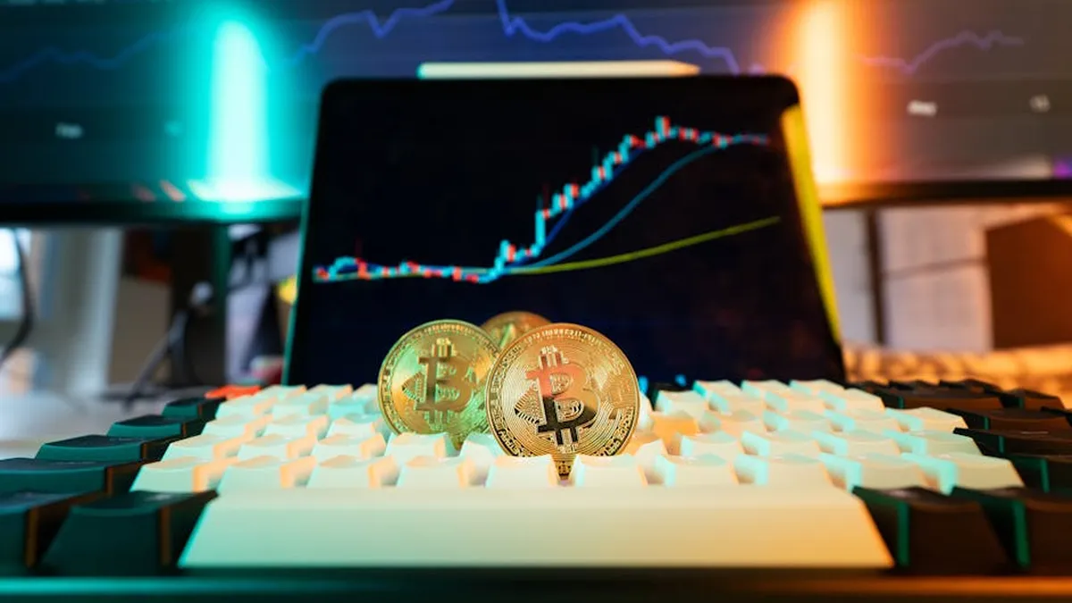 Close-up of Bitcoin coins on a keyboard with a trading chart in the background