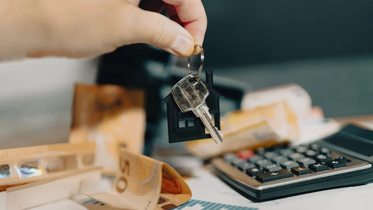 Close-up of a hand holding keys over euros and calculator, symbolizing real estate purchase.