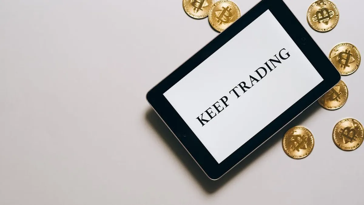 Tablet displaying 'Keep Trading' surrounded by Bitcoin coins on a white background, emphasizing digital currency and trading.
