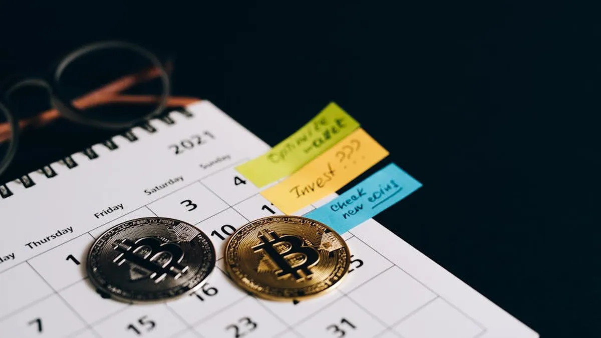 Bitcoin coins placed on a calendar with sticky notes for investment planning.