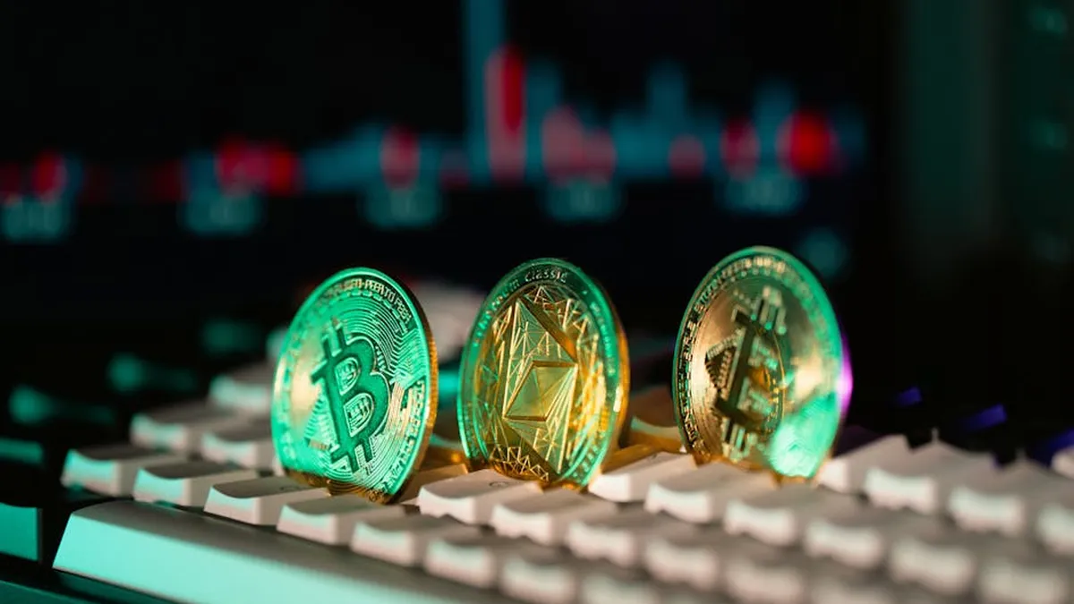 Close-up of Bitcoin and Ethereum coins placed on a keyboard, with market charts in the background.