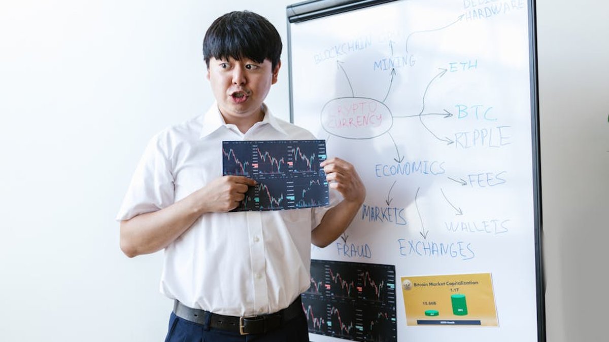 A man presenting cryptocurrency concepts on a whiteboard with charts and graphs.