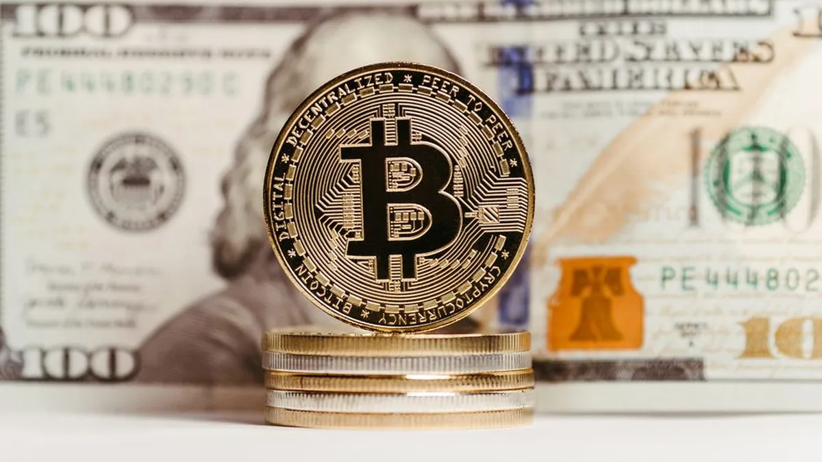 Bitcoin coin stacked with US $100 bill background, representing finance and cryptocurrency convergence.