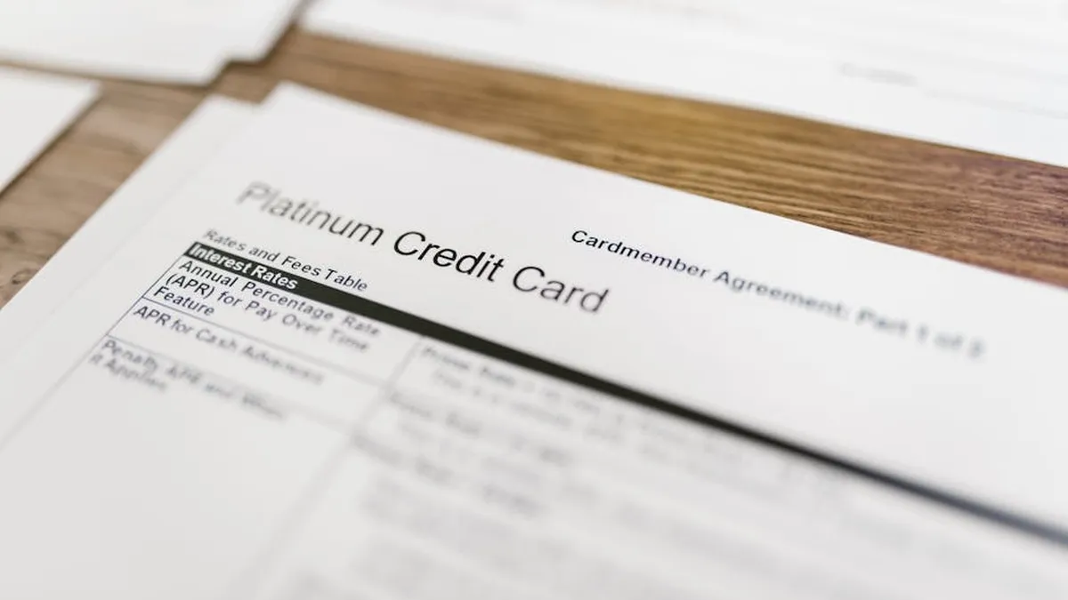 Close-up of a platinum credit card agreement document on a wooden desk.
