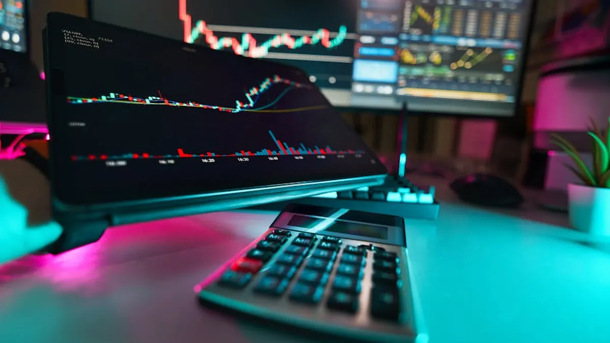 A vibrant office setup with digital tablets displaying financial analysis and stock charts, complemented by a calculator.
