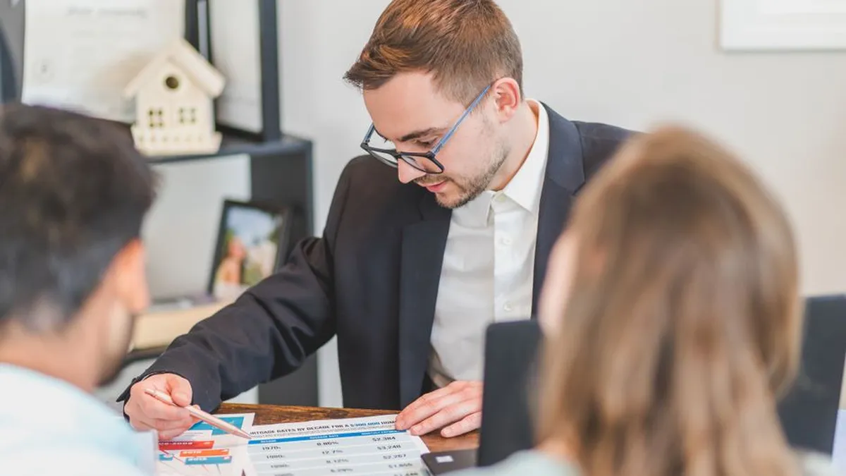 A real estate agent explains mortgage options to clients in an office setting.