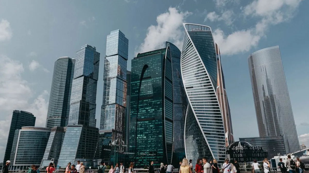 Diverse crowd stands in front of iconic modern skyscrapers in a vibrant cityscape.