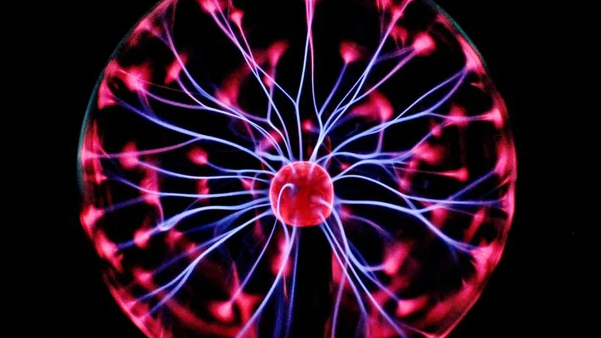 Close-up of a plasma globe with vibrant neon sparks against a dark background.