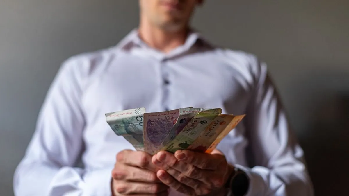 Man holding Argentine Peso banknotes in Buenos Aires, Argentina, illustrating currency concept.