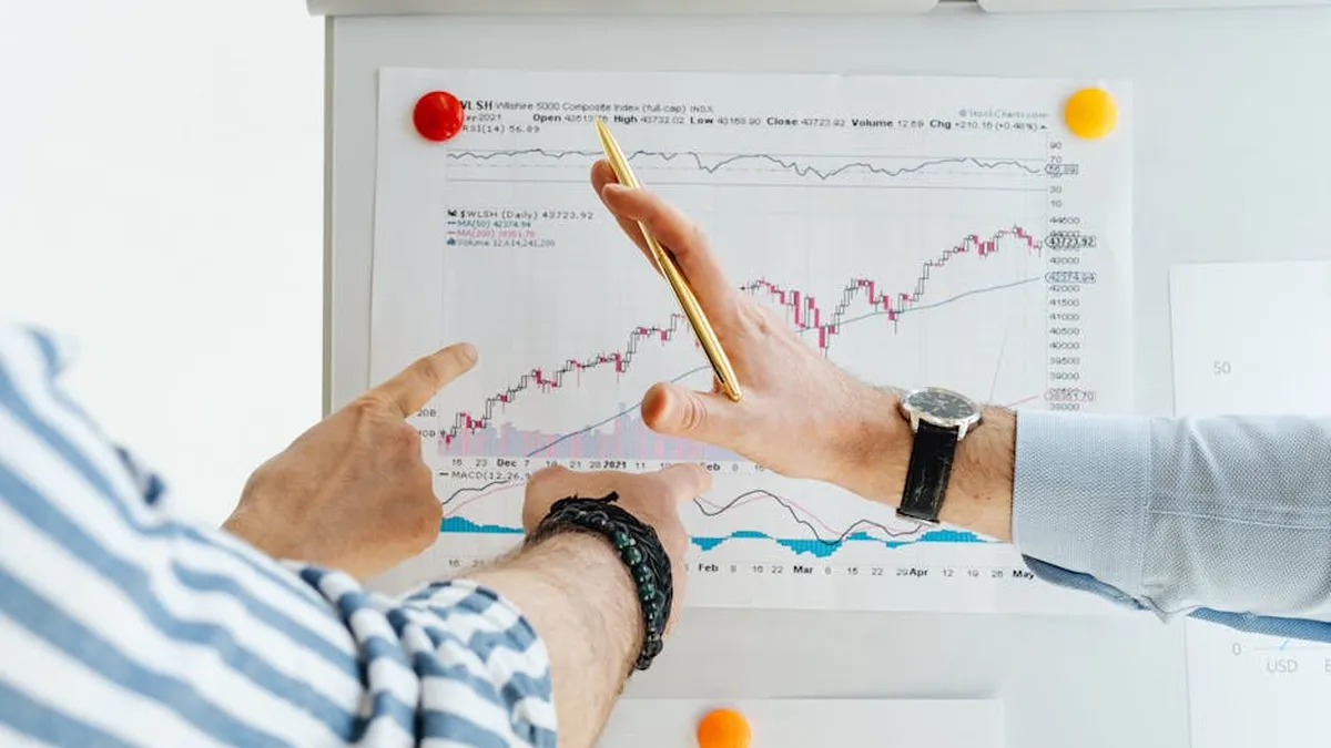 Professionals analyzing financial charts at a whiteboard meeting.