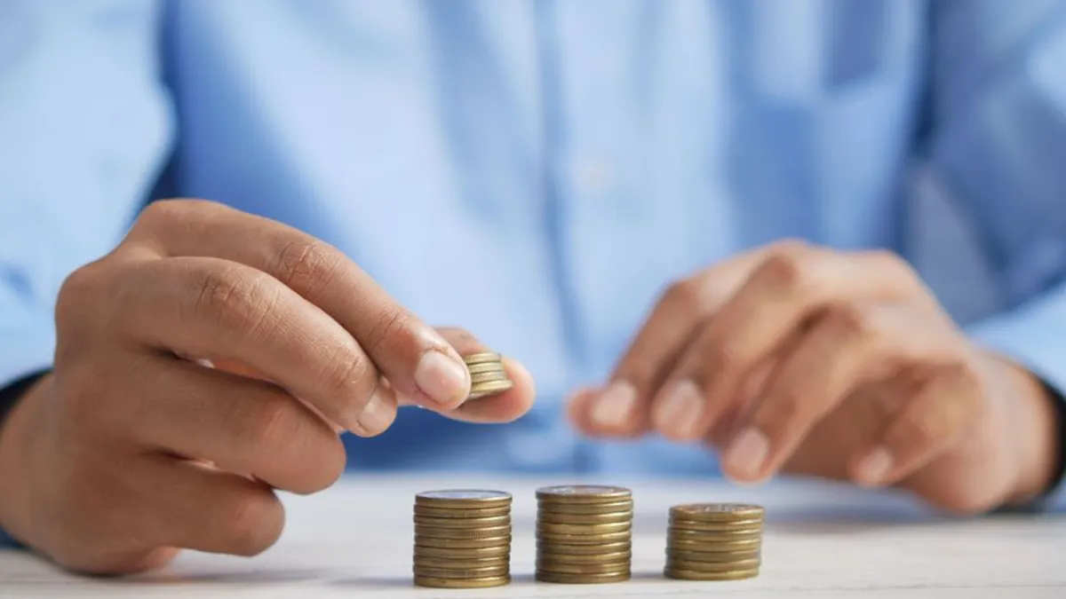 Close-up of hands stacking gold coins, symbolizing financial growth and savings.