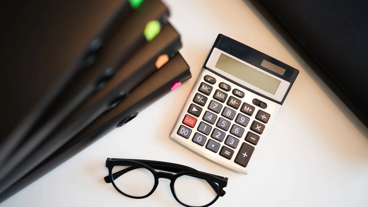 Calculator with glasses and folders on an office desk. Perfect for finance and accounting themes.