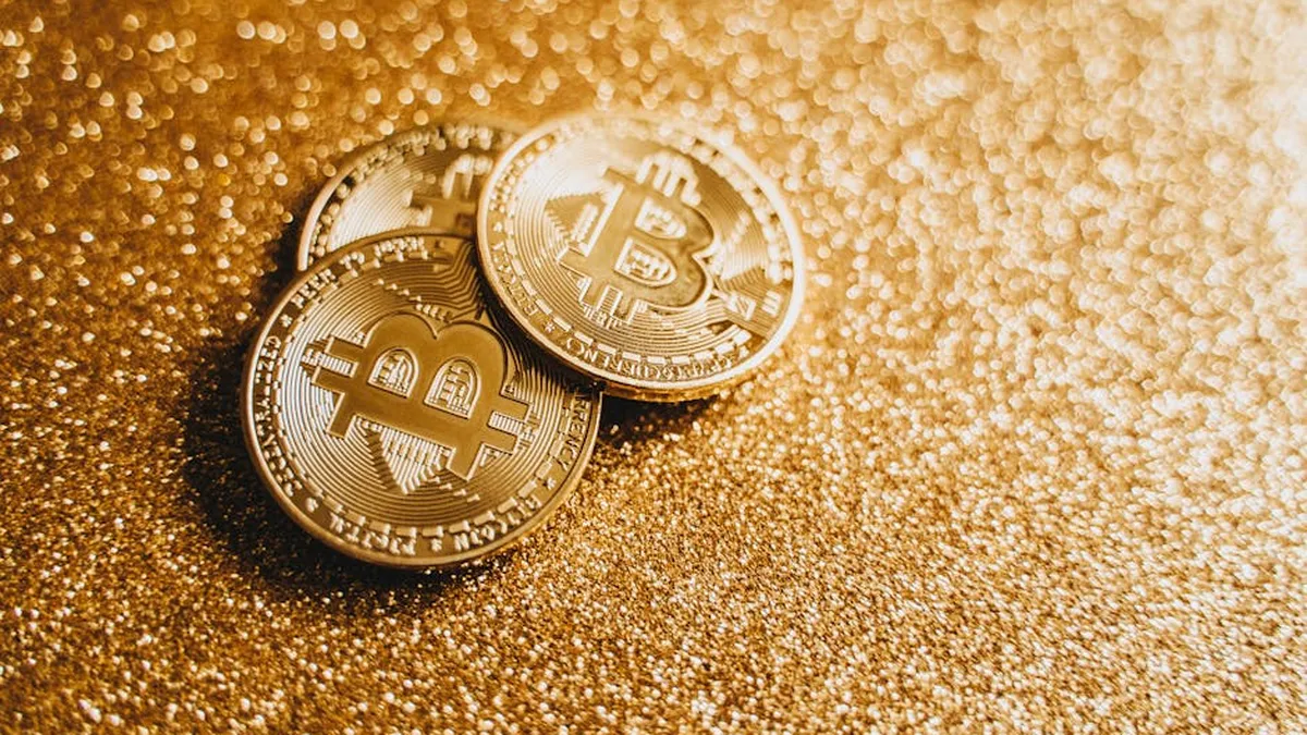 Closeup of three Bitcoin coins on a shimmering gold glitter background, symbolizing digital wealth.