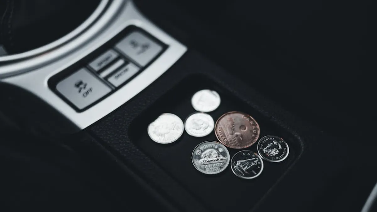 Close-up view of coins neatly placed in a car's console compartment, emphasizing currency and money themes.