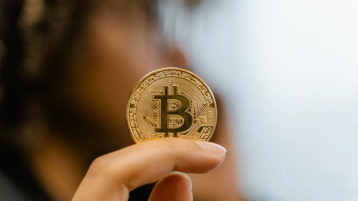 A hand holding a Bitcoin coin, representing cryptocurrency and blockchain technology investment.