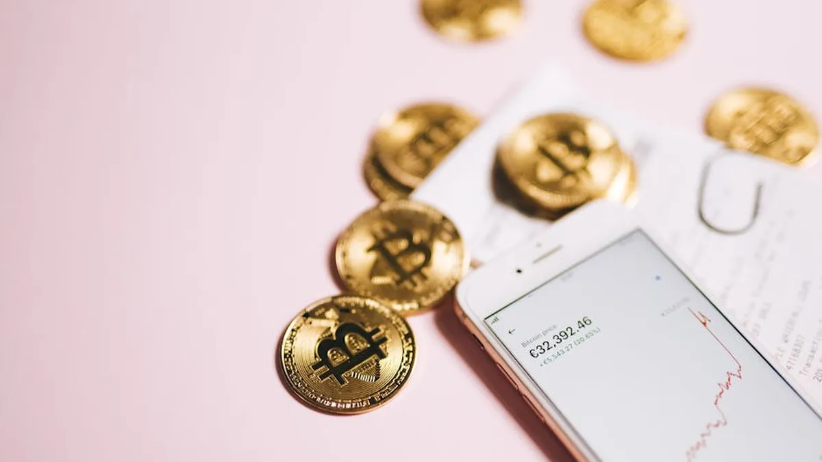 Bitcoin coins with a smartphone displaying financial data, symbolizing cryptocurrency and digital investments.