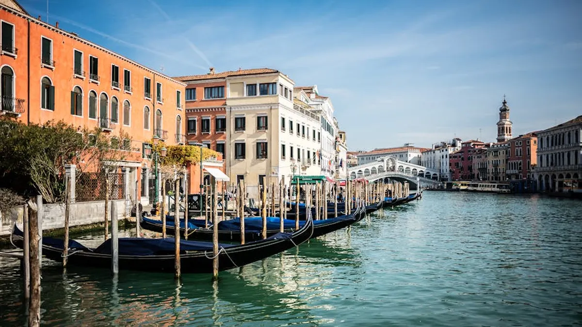 Beautiful Venetian canal view with gondolas and Rialto Bridge on a sunny day.