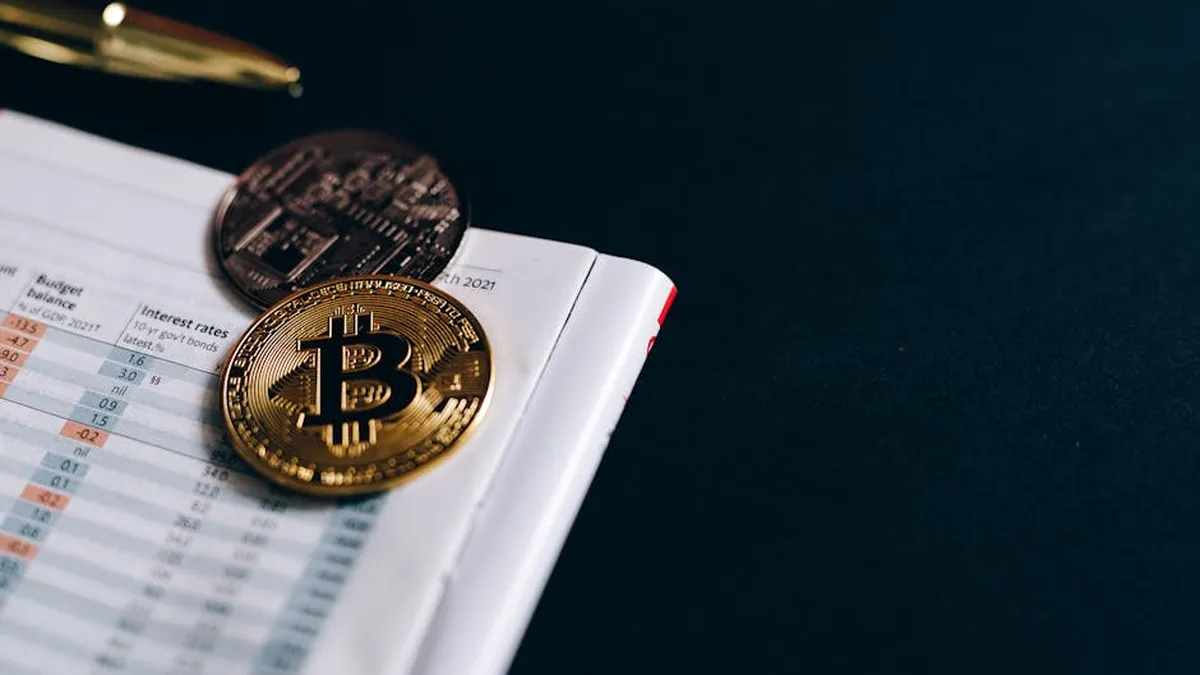 Close-up of Bitcoin coins on a financial report on a dark surface.