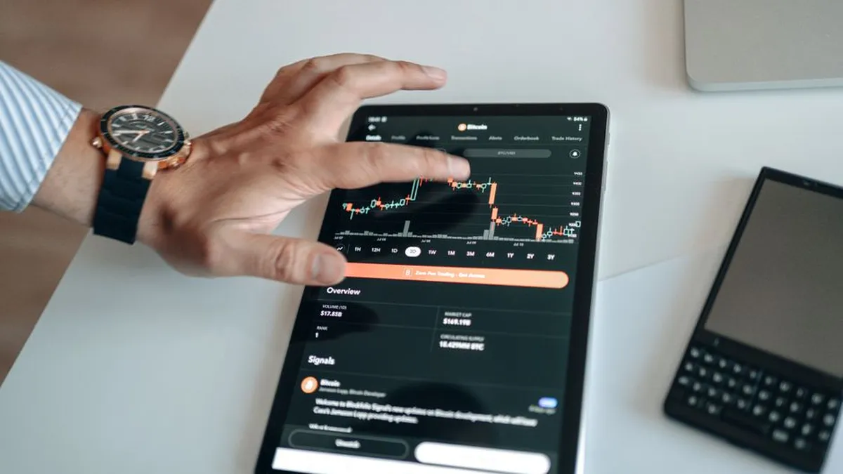 A person analyzing cryptocurrency market trends on a tablet device displaying digital charts.