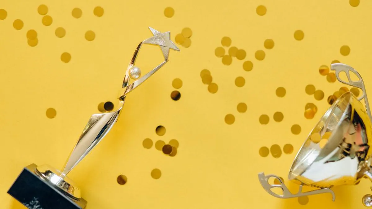 Golden trophy with celebratory confetti on a vibrant yellow background.