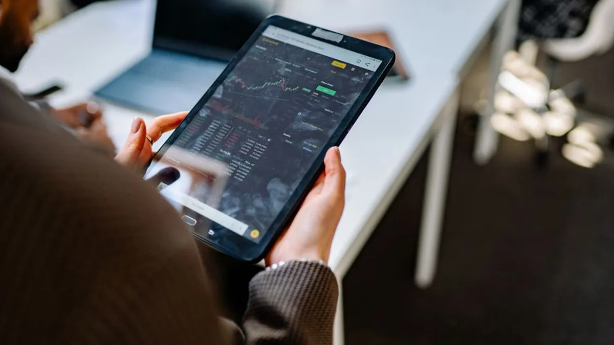 A person using a tablet for stock market analysis in an office setting.