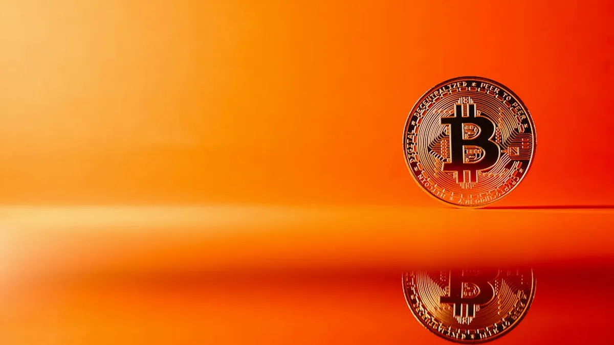 Golden Bitcoin with reflection on a bright orange background, representing digital currency concepts.